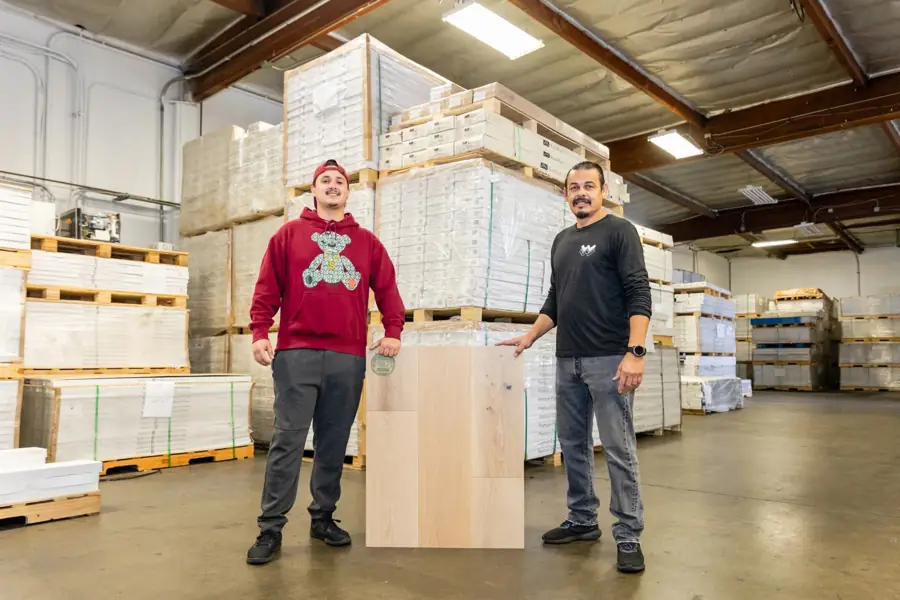 Wholesale Woodfloor Warehouse staff with an engineered hardwood plank